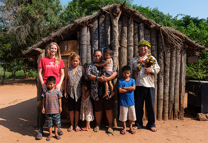 Sophie mit einigen Guarani-Kaiowá vor einer Holzhütte