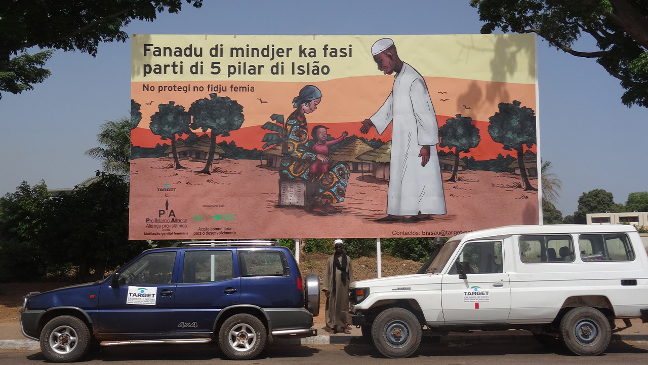 TARGETs große Plakatwand zur Aufklärungskampagne für ein Ende von FGM am Flughafen von Bissau. 