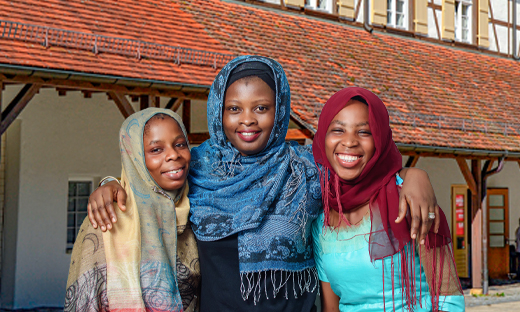 drei stark pigmentierte Mädchen mit Kopftüchern vor Haus in Baden-Württemberg